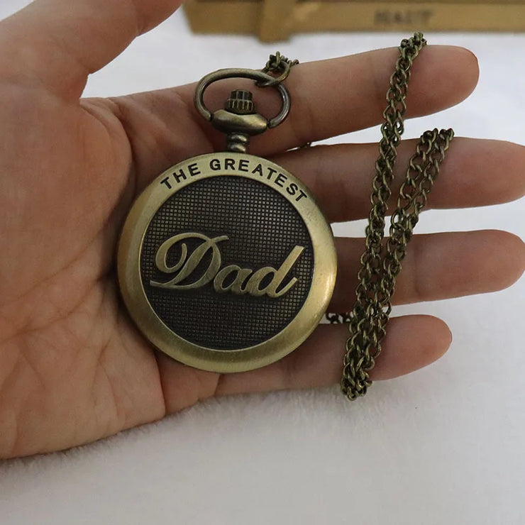 A round metallic locket with a floral pattern, shown with a matching chain on a light surface.