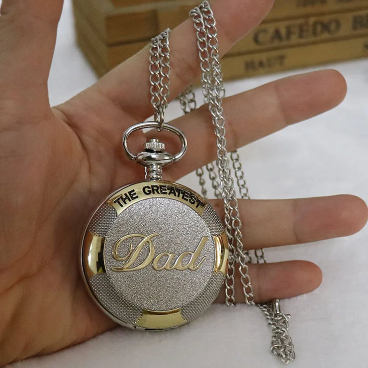 A close-up of a hand holding a small, round metallic pendant with detailed surface patterns.